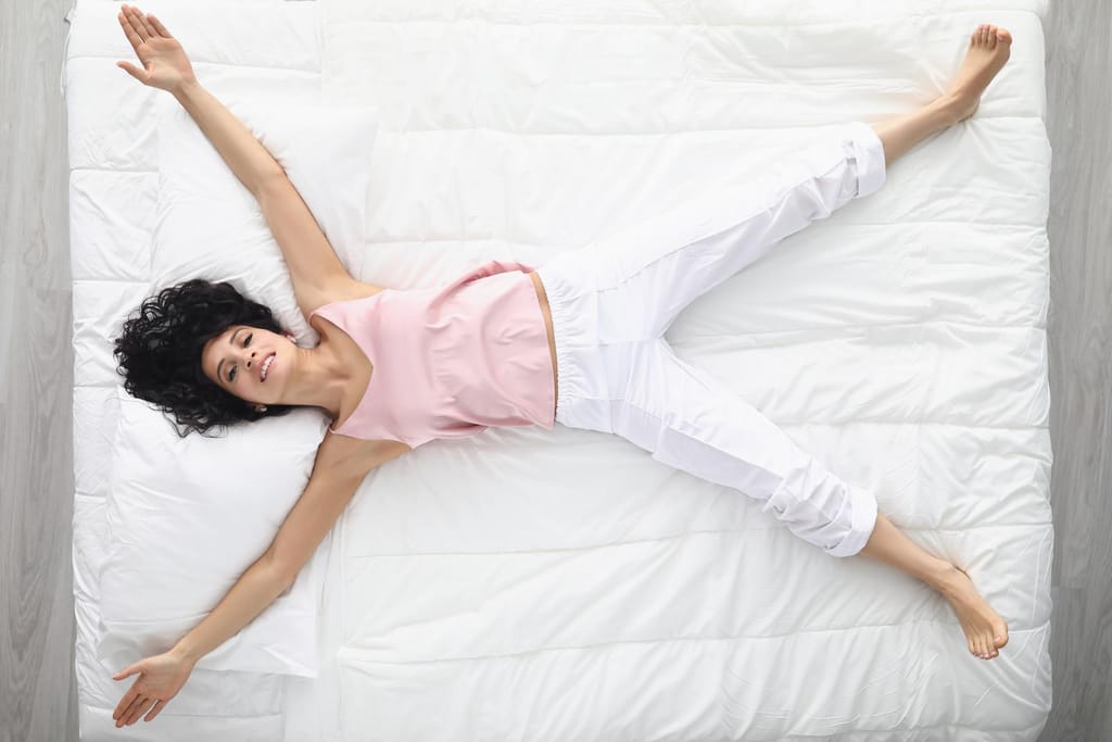 woman spreading out her arms on bed
